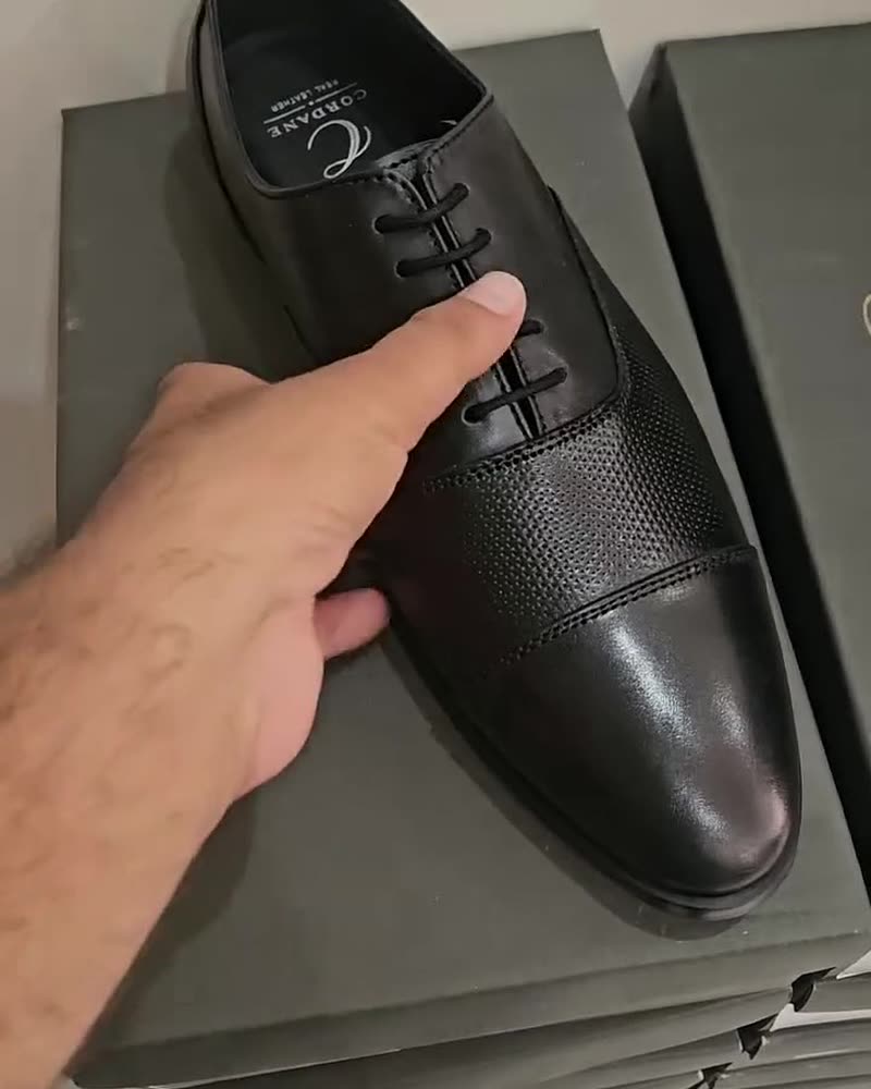 Black perforated cap-toe oxford on a Cordane box