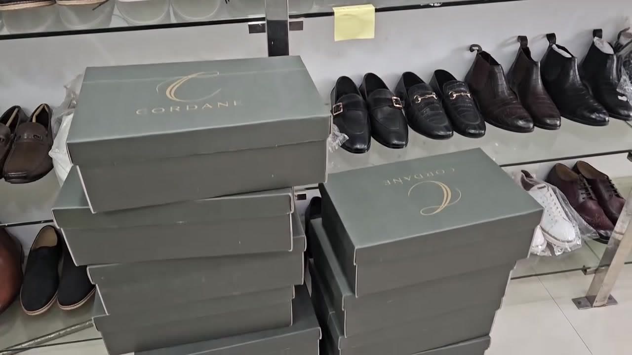 Stacked green Cordane shoe boxes in front of shoe shelves